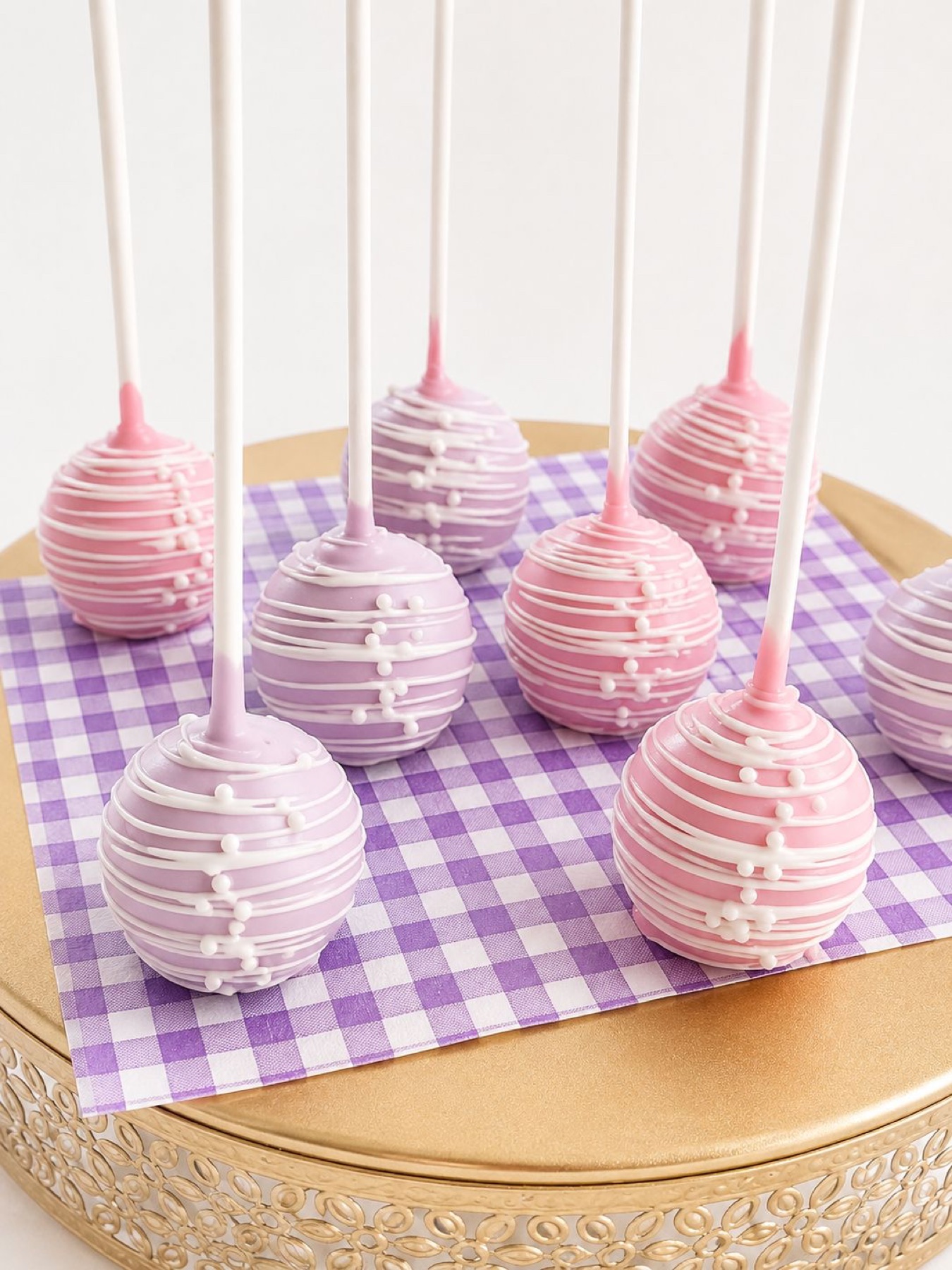 Pink and lavender cake pops with white drizzle