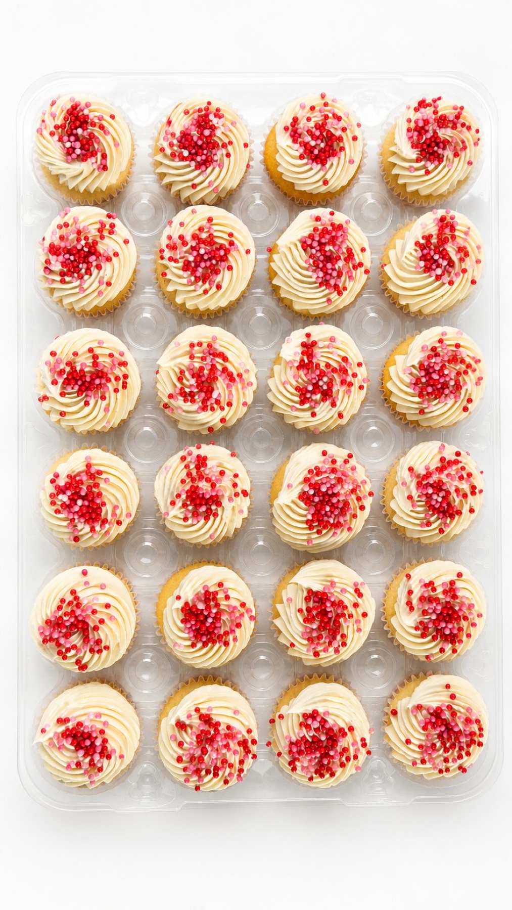 Tray of cupcakes with vanilla swirls and red sprinkles
